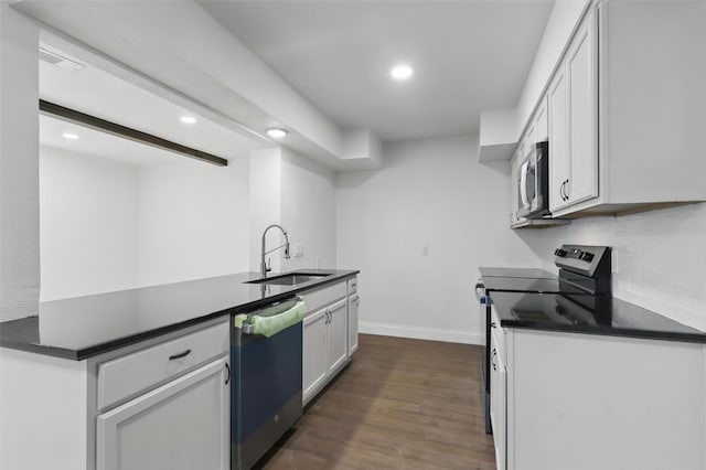 513 Edna Ct, Everman, TX 76140 - kitchen with a sink, appliances with stainless steel finishes, dark countertops, recessed lighting, and dark wood-type flooring