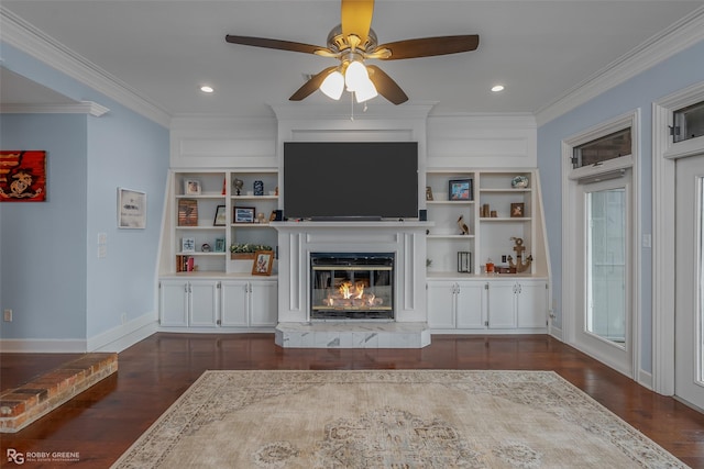 living area with ornamental molding, dark wood-style flooring, baseboards, a glass covered fireplace, and a ceiling fan