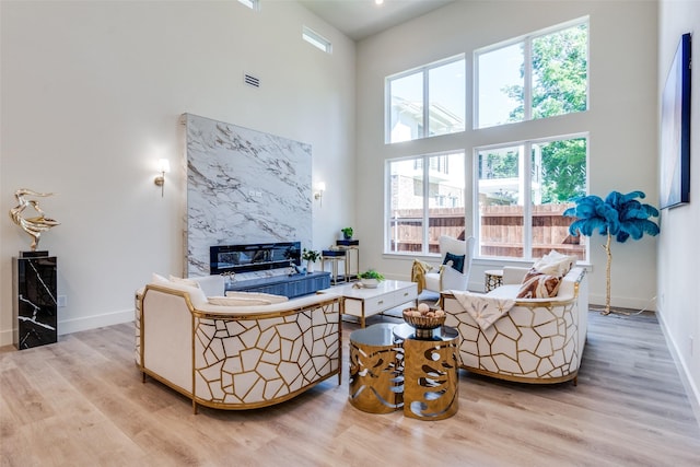 13554 Pyramid Dr, Farmers Branch, TX 75234 - living area with a premium fireplace, a towering ceiling, plenty of natural light, wood finished floors, and baseboards