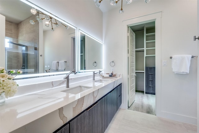 13554 Pyramid Dr, Farmers Branch, TX 75234 - bathroom featuring a shower stall, double vanity, a spacious closet, and wood finished floors