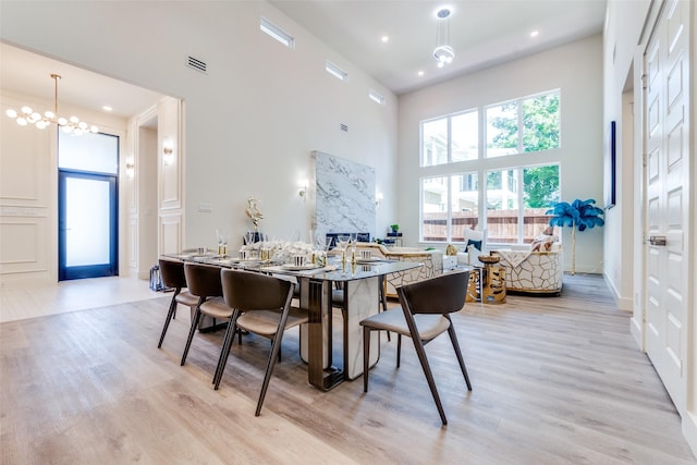13554 Pyramid Dr, Farmers Branch, TX 75234 - dining room featuring a towering ceiling, light wood-style floors, a chandelier, and a fireplace