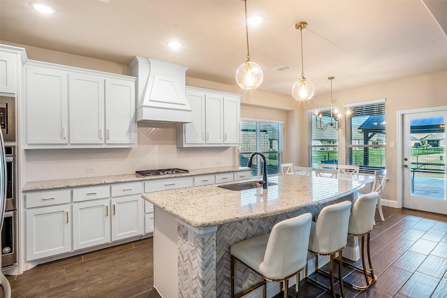 208 Johnson St, Granbury, TX 76048 - kitchen with stainless steel appliances, a sink, custom exhaust hood, white cabinetry, and decorative backsplash