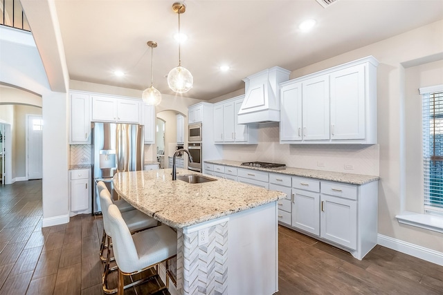 208 Johnson St, Granbury, TX 76048 - kitchen with arched walkways, custom range hood, appliances with stainless steel finishes, a sink, and decorative backsplash