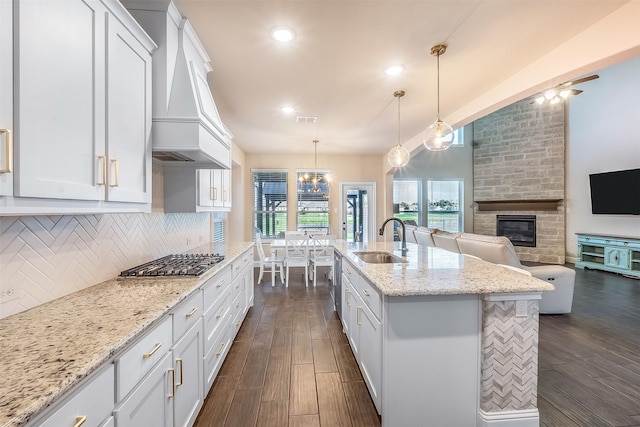 208 Johnson St, Granbury, TX 76048 - kitchen with a sink, custom exhaust hood, stainless steel gas cooktop, a fireplace, and tasteful backsplash