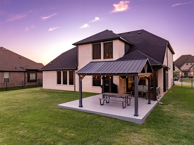 208 Johnson St, Granbury, TX 76048 - back of house at dusk with brick siding, a patio area, and a shingled roof