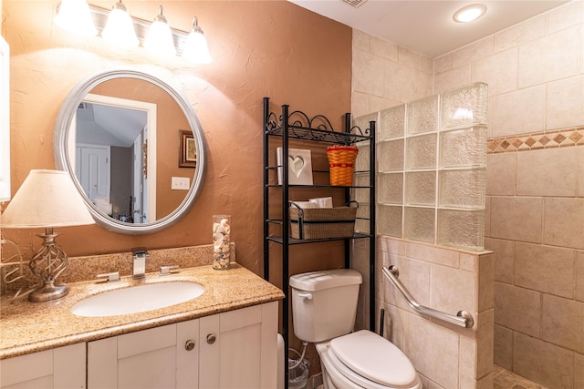 bathroom with a textured wall, walk in shower, toilet, and vanity