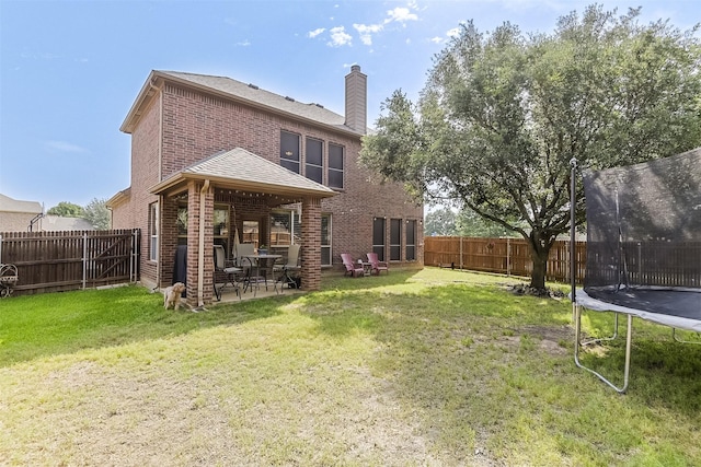 8306 Pecan Creek Dr, Arlington, TX 76001 - back of property featuring a trampoline, brick siding, a chimney, and a patio area