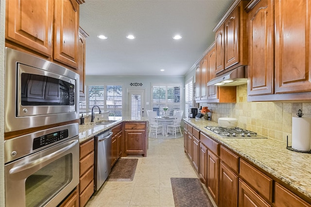 8306 Pecan Creek Dr, Arlington, TX 76001 - kitchen featuring stainless steel appliances, a sink, a peninsula, decorative backsplash, and light stone counters