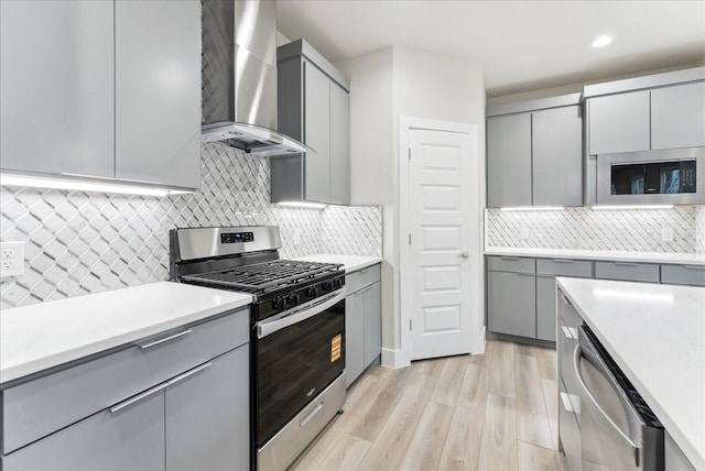 1903 Varsity Dr, Grand Prairie, TX 75051 - kitchen featuring gray cabinetry, stainless steel appliances, wall chimney exhaust hood, tasteful backsplash, and recessed lighting