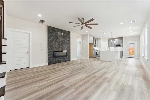1903 Varsity Dr, Grand Prairie, TX 75051 - unfurnished living room with a high end fireplace, a sink, ceiling fan, light wood-type flooring, and baseboards