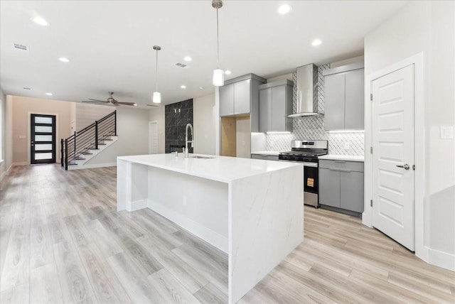 1903 Varsity Dr, Grand Prairie, TX 75051 - kitchen featuring wall chimney range hood, stainless steel gas range, gray cabinets, a sink, and light wood-type flooring