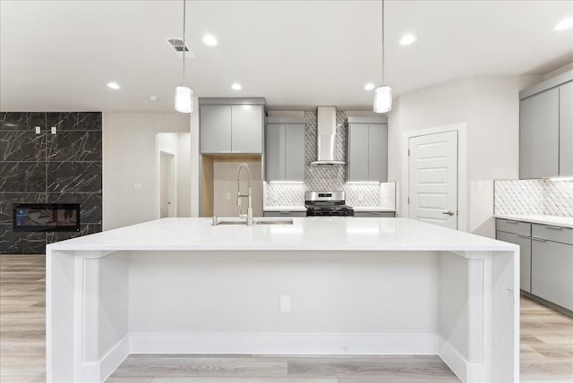 1903 Varsity Dr, Grand Prairie, TX 75051 - kitchen with gray cabinetry, a sink, wall chimney exhaust hood, stainless steel range with gas cooktop, and recessed lighting