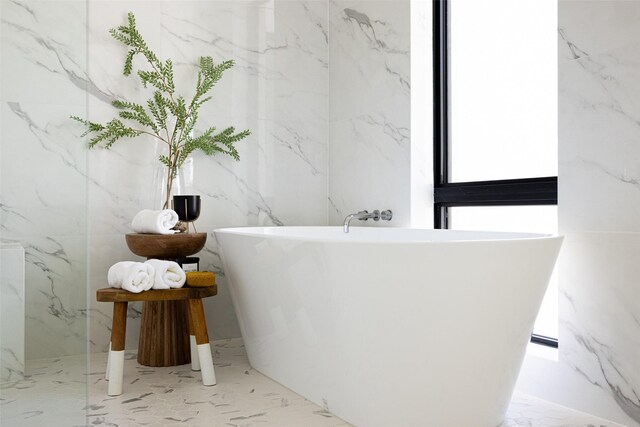 610 N Oak Cliff Blvd Unit 301, Dallas, TX 75208 - full bathroom featuring stone wall, marble tiled flooring, a freestanding bath, and healthy amount of natural light