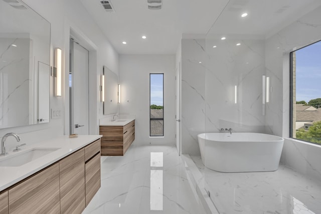 610 N Oak Cliff Blvd Unit 301, Dallas, TX 75208 - bathroom with healthy amount of natural light, recessed lighting, two vanities, marble tiled floors, and a freestanding tub