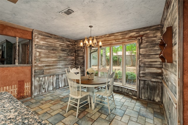 dining space with stone finish floors and a chandelier