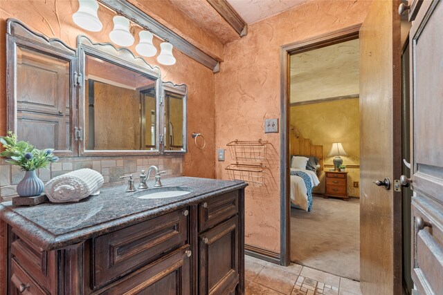 bathroom featuring a textured wall, vanity, connected bathroom, and decorative backsplash