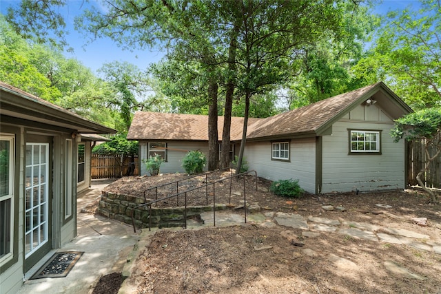 view of front of property with an outdoor structure, fence, and roof with shingles