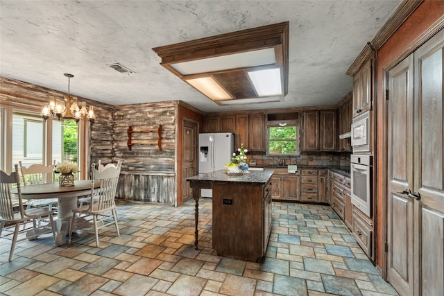 kitchen featuring white appliances, a kitchen breakfast bar, a center island, a chandelier, and pendant lighting