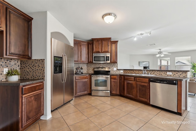 4006 Autumnwood Ln, Heartland, TX 75126 - kitchen with appliances with stainless steel finishes, dark countertops, a peninsula, and tasteful backsplash