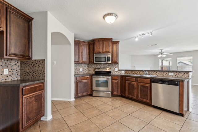 4006 Autumnwood Ln, Heartland, TX 75126 - kitchen with appliances with stainless steel finishes, dark countertops, a peninsula, a sink, and light tile patterned floors