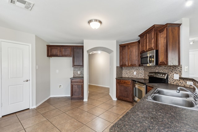 4006 Autumnwood Ln, Heartland, TX 75126 - kitchen with stainless steel appliances, a sink, arched walkways, and dark countertops