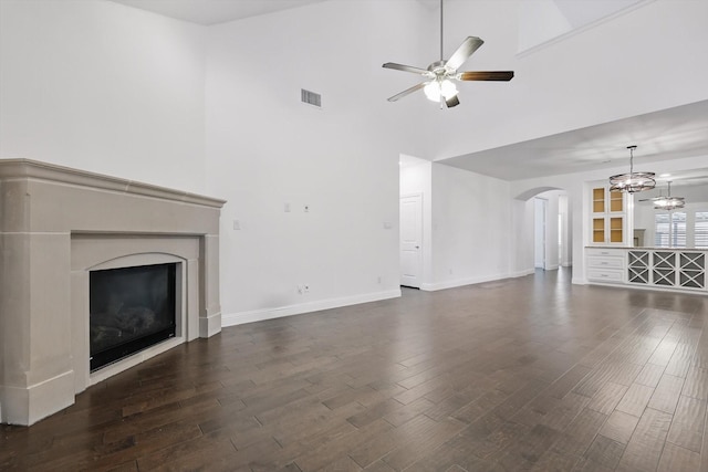 9808 Denali Dr, Little Elm, TX 75068 - unfurnished living room with arched walkways, high vaulted ceiling, ceiling fan, a high end fireplace, and dark wood-style floors