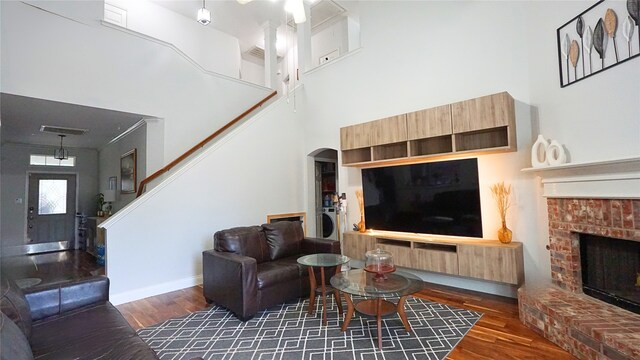 6920 Willow Crest Dr, Mckinney, TX 75070 - living room featuring wood finished floors, a fireplace, baseboards, arched walkways, and a towering ceiling
