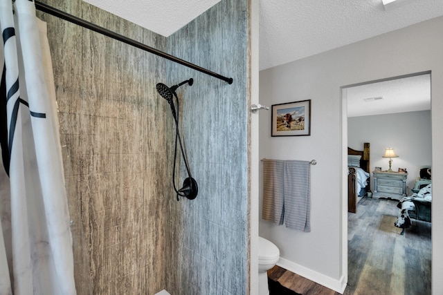 6199 State Highway 22, Hillsboro, TX 76645 - bathroom featuring a tile shower, toilet, wood finished floors, ensuite bathroom, and a textured ceiling