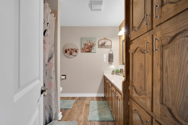 6199 State Highway 22, Hillsboro, TX 76645 - full bathroom featuring baseboards, vanity, wood finished floors, a textured ceiling, and toilet