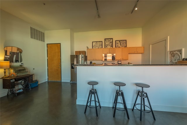 2502 Live Oak St Unit 314, Dallas, TX 75204 - kitchen featuring appliances with stainless steel finishes, track lighting, concrete flooring, dark countertops, and a kitchen breakfast bar