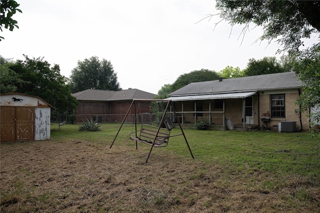 1219 Daisy Ln, Irving, TX 75061 - rear view of house with a playground, brick siding, a storage shed, and central AC