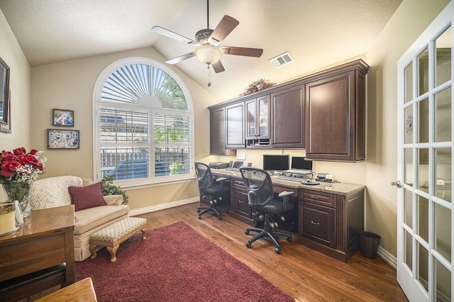 home office featuring dark wood-style flooring, lofted ceiling, a ceiling fan, built in desk, and baseboards