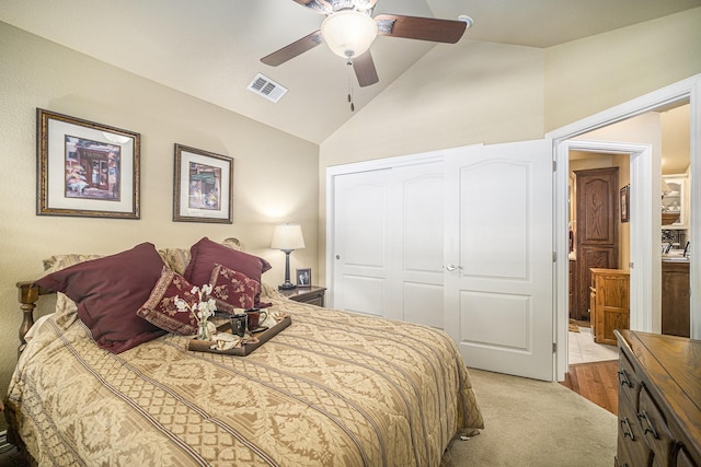 bedroom featuring a closet, lofted ceiling, light carpet, and a ceiling fan