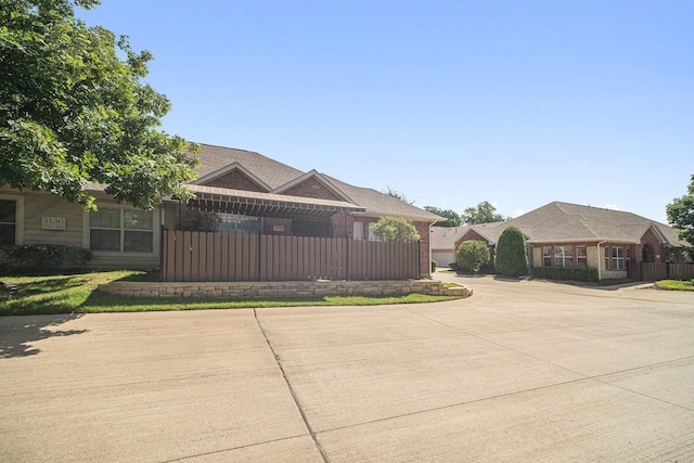 view of front of house with brick siding, fence, and curved driveway