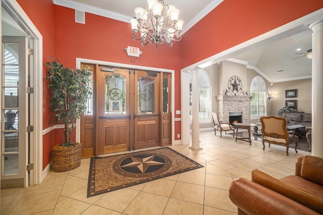 tiled entrance foyer with decorative columns, ornamental molding, a fireplace, baseboards, and a chandelier