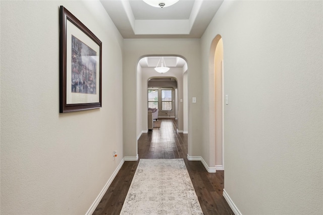 307 Acadia Ln, Forney, TX 75126 - hall featuring arched walkways, dark wood-style flooring, baseboards, and a tray ceiling