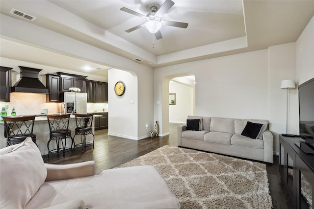 307 Acadia Ln, Forney, TX 75126 - living area featuring arched walkways, a ceiling fan, dark wood-style floors, baseboards, and a raised ceiling