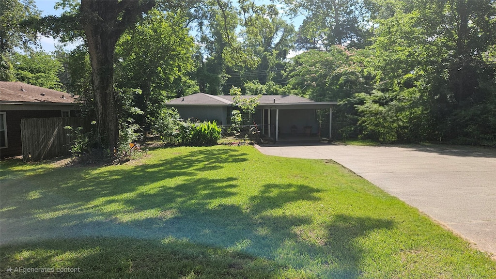 view of green lawn with driveway and an attached carport