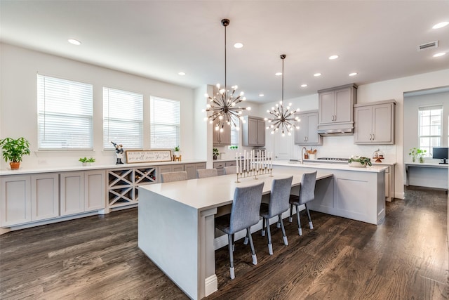 8416 Shoreacres Dr, Mckinney, TX 75070 - kitchen featuring gray cabinetry, under cabinet range hood, a chandelier, dark wood-style floors, and light countertops