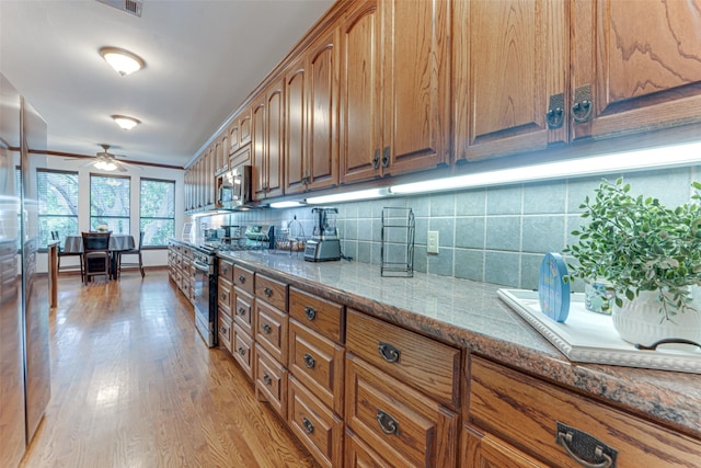 4402 Running Brook Dr, Rowlett, TX 75088 - kitchen with appliances with stainless steel finishes, stone counters, decorative backsplash, brown cabinetry, and light wood-style flooring