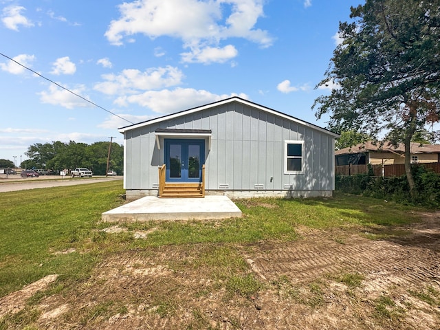1209 N Morris St, Gainesville, TX 76240 - back of house with french doors, a lawn, board and batten siding, and entry steps