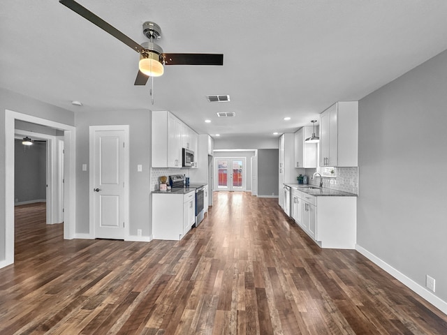 1209 N Morris St, Gainesville, TX 76240 - kitchen with stainless steel appliances, a ceiling fan, a sink, dark wood-style floors, and decorative backsplash
