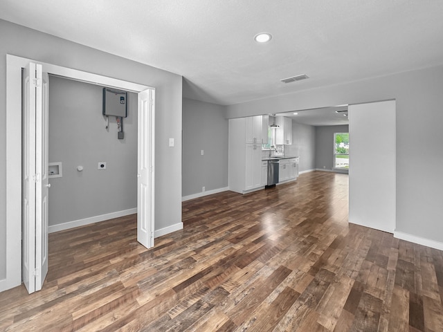 1209 N Morris St, Gainesville, TX 76240 - unfurnished living room featuring dark wood-style flooring, baseboards, recessed lighting, and a sink