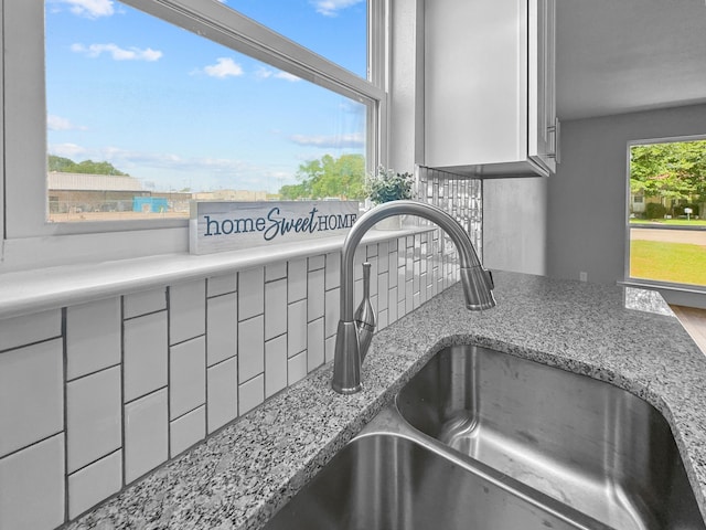 1209 N Morris St, Gainesville, TX 76240 - kitchen view of a sink, tasteful backsplash, light stone countertops, and gray cabinetry