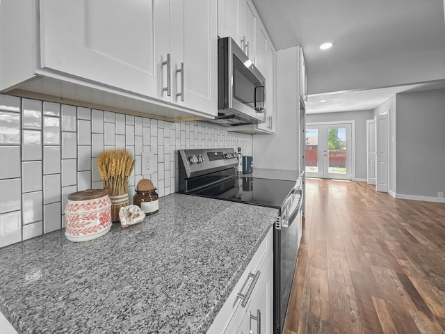 1209 N Morris St, Gainesville, TX 76240 - kitchen with appliances with stainless steel finishes, recessed lighting, white cabinets, light stone countertops, and tasteful backsplash