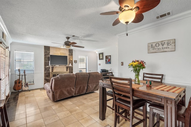 1104 Harwell Dr Unit 1514, Arlington, TX 76011 - dining room featuring ceiling fan, crown molding, a textured ceiling, light tile patterned flooring, and a large fireplace