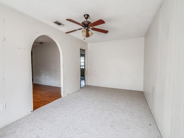 2203 Gould Ave, Fort Worth, TX 76164 - carpeted spare room featuring ceiling fan, arched walkways, a textured ceiling, and wooden walls