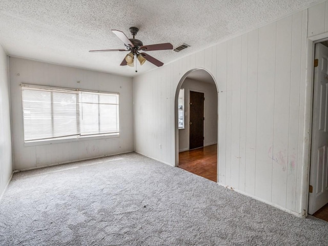 2203 Gould Ave, Fort Worth, TX 76164 - carpeted spare room featuring a textured ceiling, arched walkways, ceiling fan, and wooden walls