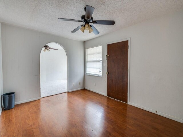 2203 Gould Ave, Fort Worth, TX 76164 - empty room featuring arched walkways, ceiling fan, wood finished floors, baseboards, and a textured ceiling