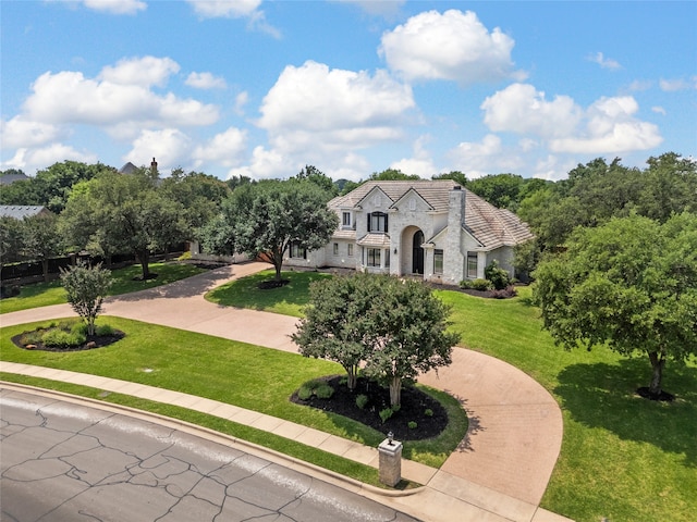 6021 Canyon Trl, Waco, TX 76657 - french country home with stone siding, a front lawn, and curved driveway